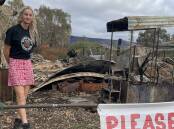 Jemma Purcell by the historic train carriage from the 1800s burned in the February 2024 fires. It used to house the performing artists at Wild Misty Mountain. Picture Sheryl Lowe. 