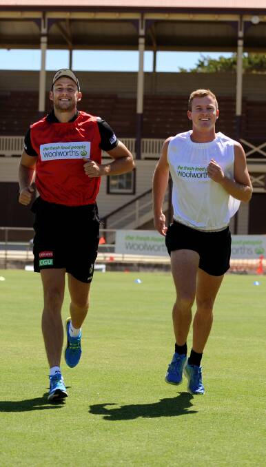 Off and running: Collingwood's Ben Reid and 2012 Stawell Gift Winner Matt Wiltshire jog across Central Park to promote the event. Picture: SAMANTHA CAMARRI.