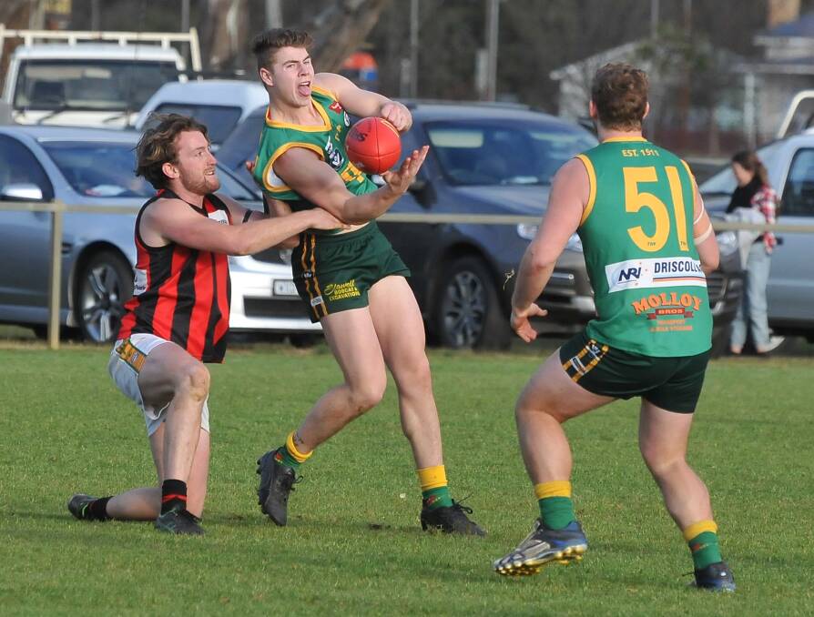 Tackled: Cody Driscoll does his best to get his handball away despite being tackled by his Maldon opponent. Navarre went on to win by 157 points. Picture: MARK MCMILLAN