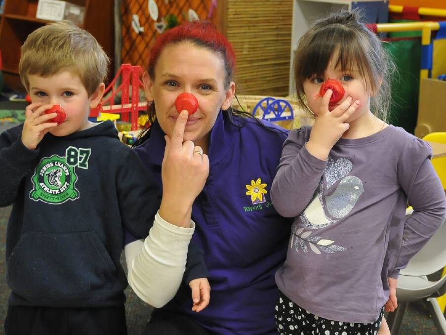 RED NOSE DAY: Kendal, Sam and Tyler hold their handmade red noses onto their faces during the 'party' at Taylors Gully Childcare Centre.