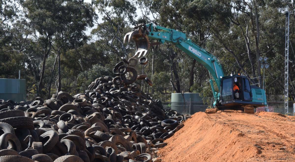 ACTION: An excavator picks up some tyres from the giant stockpile and moves them into a truck- ready to be taken to Melbourne. Picture: Rex Martinich 