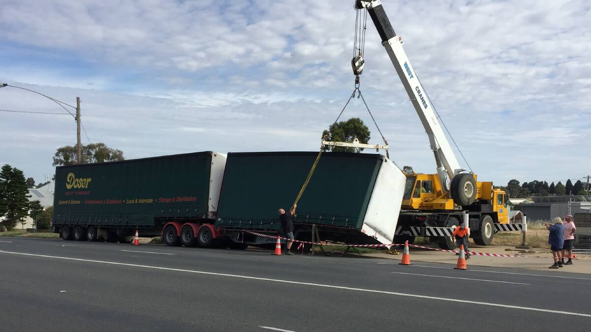 FALLEN THROUGH: A crane attempts to lift this trailer out of an unfortunate situation. Photo: Anthony Piovesan