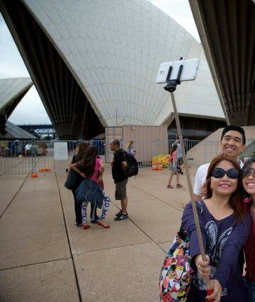 Family pic: Tourists using selfie sticks. Audrey Amparo uses a selfie stick to photograph her family at the Opera House.  Photo: Wolter Peeters