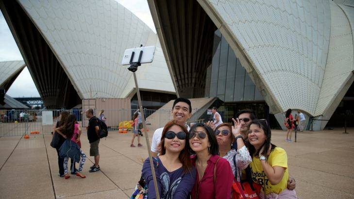 Family pic: Tourists using selfie sticks. Audrey Amparo uses a selfie stick to photograph her family at the Opera House.  Photo: Wolter Peeters