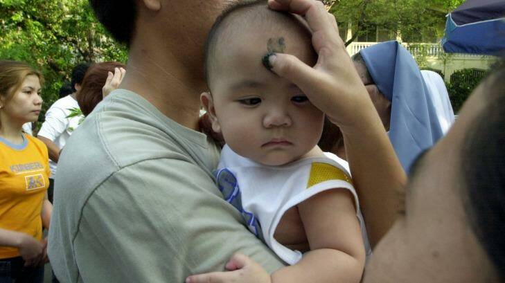 A nun places the sign of the cross sign on on a child's head in Manila, the Philippines.  Photo: Aaron Favila