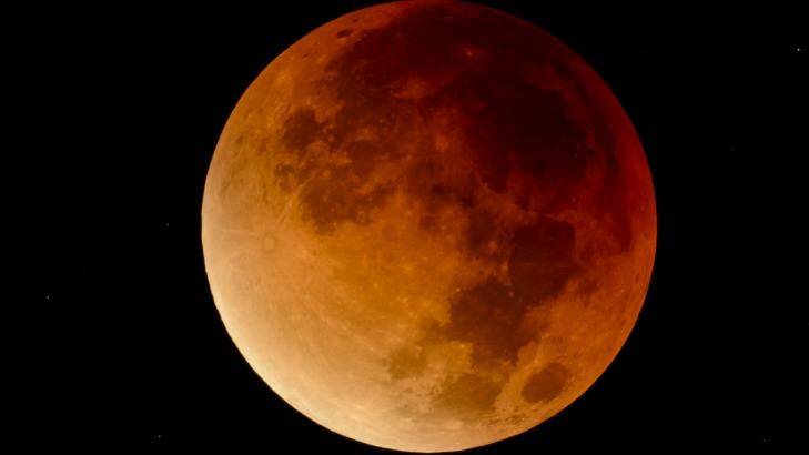 The perigee full moon, or supermoon appears red on a previous autumn sky. Photo: Peter Komka, AP