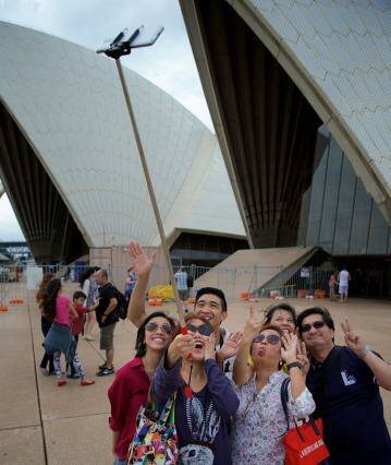 Great trick: Tourists using selfie sticks. Audrey Amparo uses a selfie stick to photograph her family at the Opera House.  Photo: Wolter Peeters