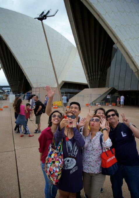 Great trick: Tourists using selfie sticks. Audrey Amparo uses a selfie stick to photograph her family at the Opera House.  Photo: Wolter Peeters