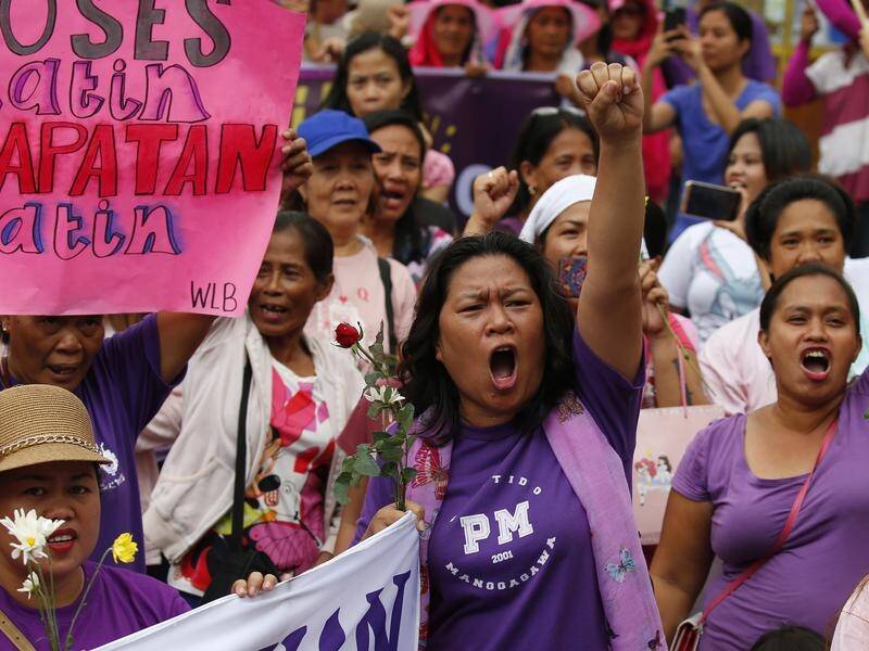 Hundreds of Filipino women in pink and purple shirts are protesting on International Women's Day.