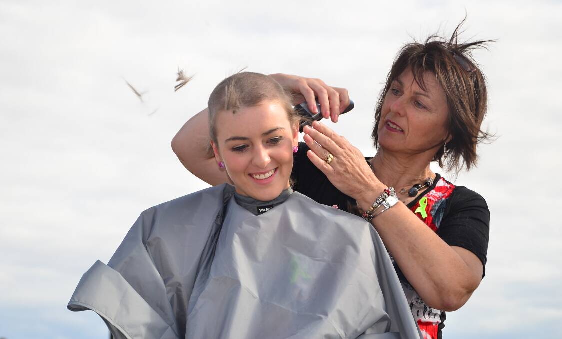 Deb Carey puts the finishing touches on her niece Greta Carey's head shave at the Stawell Gold Cup meeting on Easter Sunday. Picture: MARK McMILLAN. 