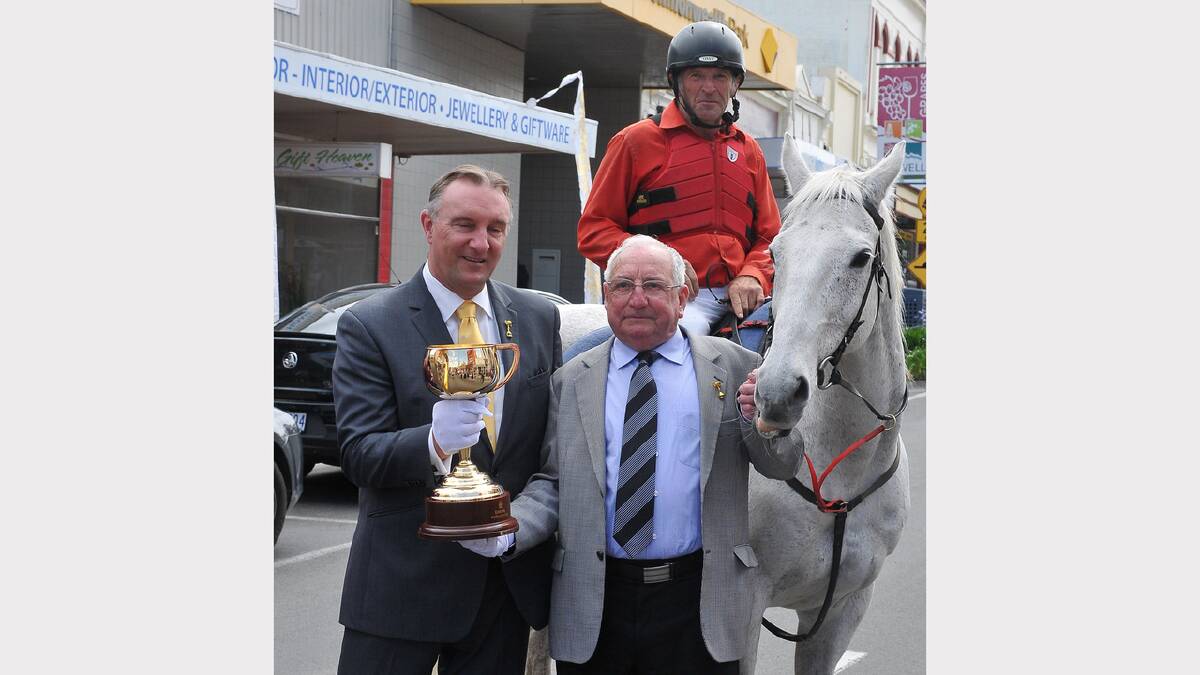 Former chief executive of the Victoria Racing Club, Dale Monteith and two time Melbourne Cup winning trainer Mick Robins, hold the cup in front of Danny the horse and his rider High O'Sullivan.