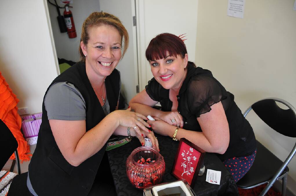 Tracey Barber (left) gets her fingernails painted red by Kim Salmi from Hello Gorgeous as part of the 'Kiss MS Goodbye' fundraiser. Picture: BEN KIMBER