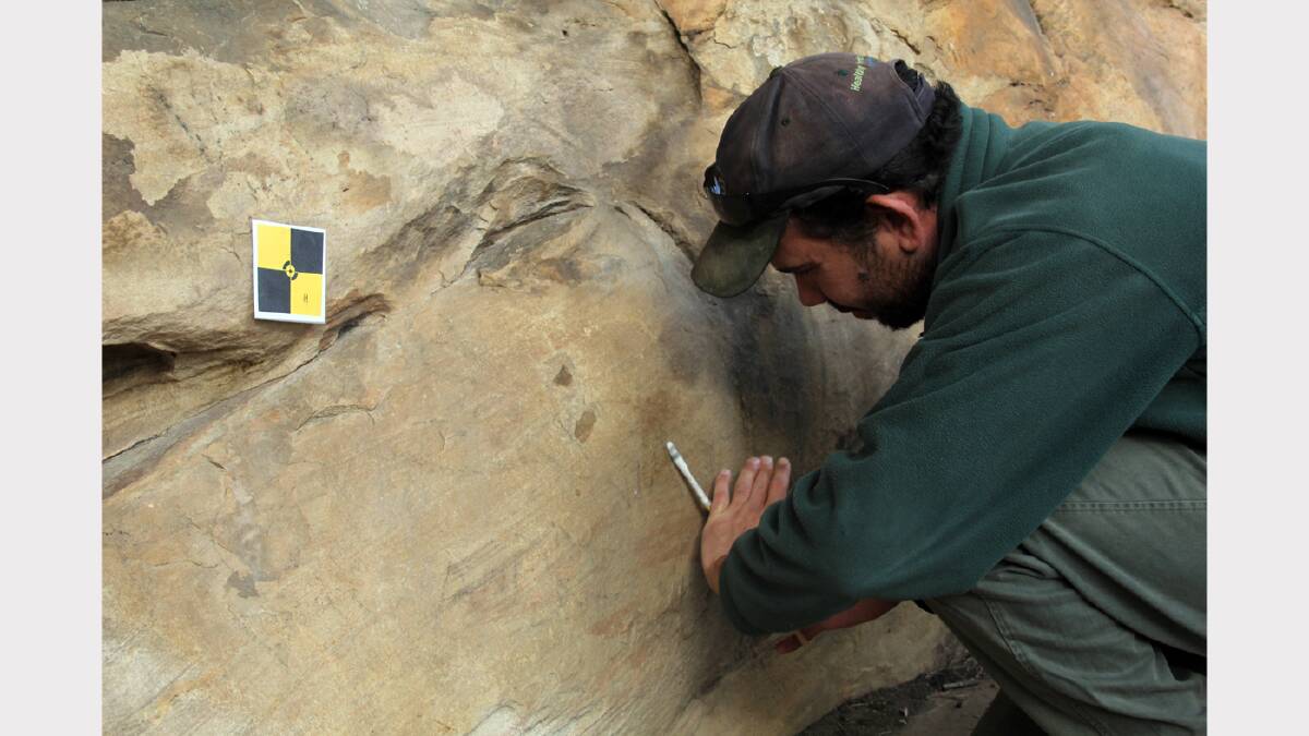 Jake Goodes cleans off some graffiti at a rock-art site in the Grampians.