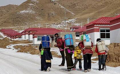 Tibetan girls carry water to their new homes in a resettlement village.