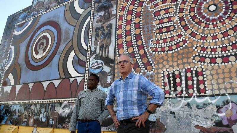 Prime Minister Malcolm Turnbull is shown a community mural by traditional owner Ronald Plummer (left) at Tennant Creek, in the Northern Territory. Photo: AAP Image/Dan Himbrechts