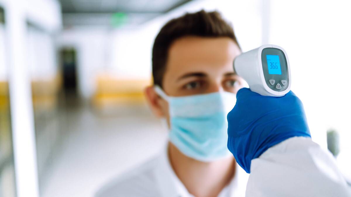 hecking the temperature of office workers during the coronavirus pandemic. Photo: Shutterstock