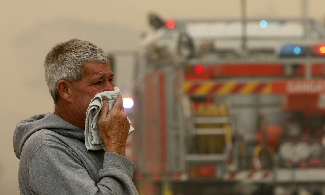 A resident watches the progress of bushfires near houses in Old Bar, NSW, on Saturday. Picture: AAP