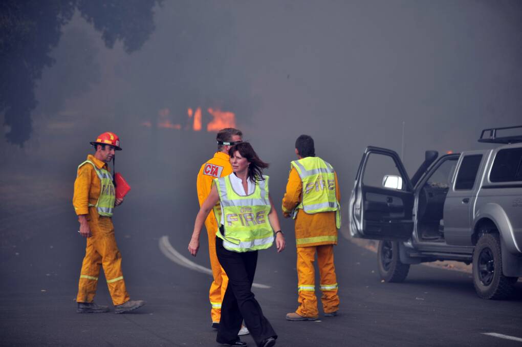 Emergency service teams at Happy Valley Road watch as the fire claims another structure> Picture: PETER HYETT