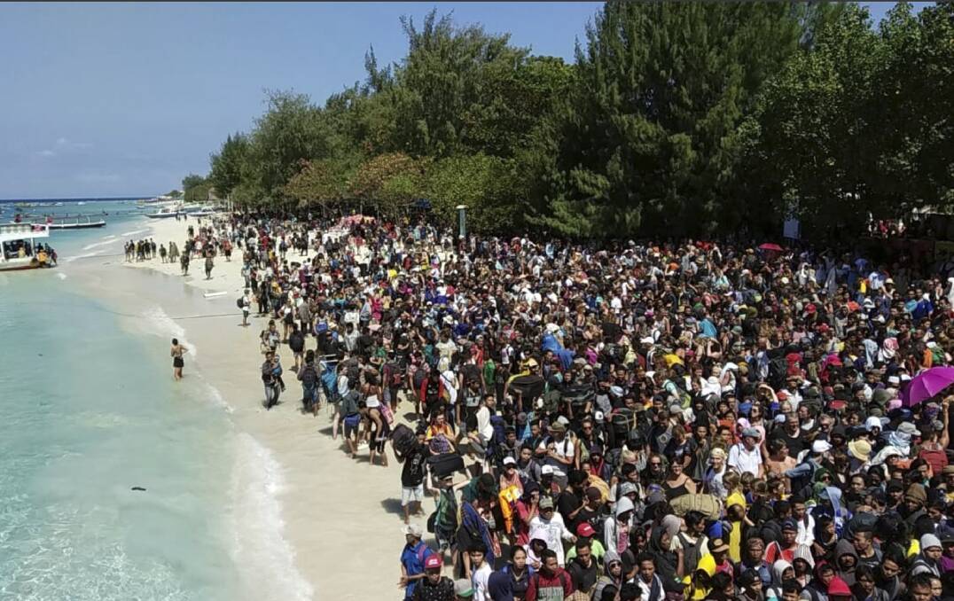 WAIT: Tourists affected by a strong earthquake line up on a beach as they wait to be evacuated from Gili Trawangan Island on Monday. Picture: INDONESIAN MARINE POLICE