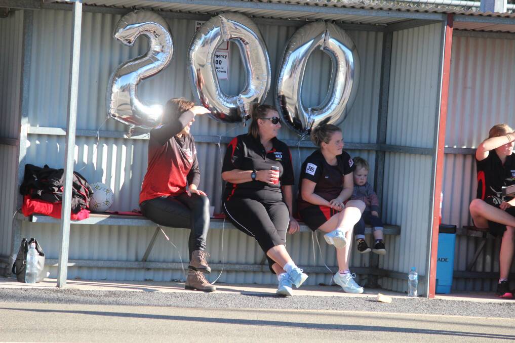 Tracey Dark, Toni Stewart and Madi Freeland sit in front of balloons celebrating Jade Cross' 200th A Grade game. Picture: LACHLAN WILLIAMS