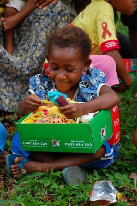 GRATEFUL: A child in Papua New Guinea opens a shoebox of goodies, donated through the Operation Christmas Child project. Picture: CONTRIBUTED