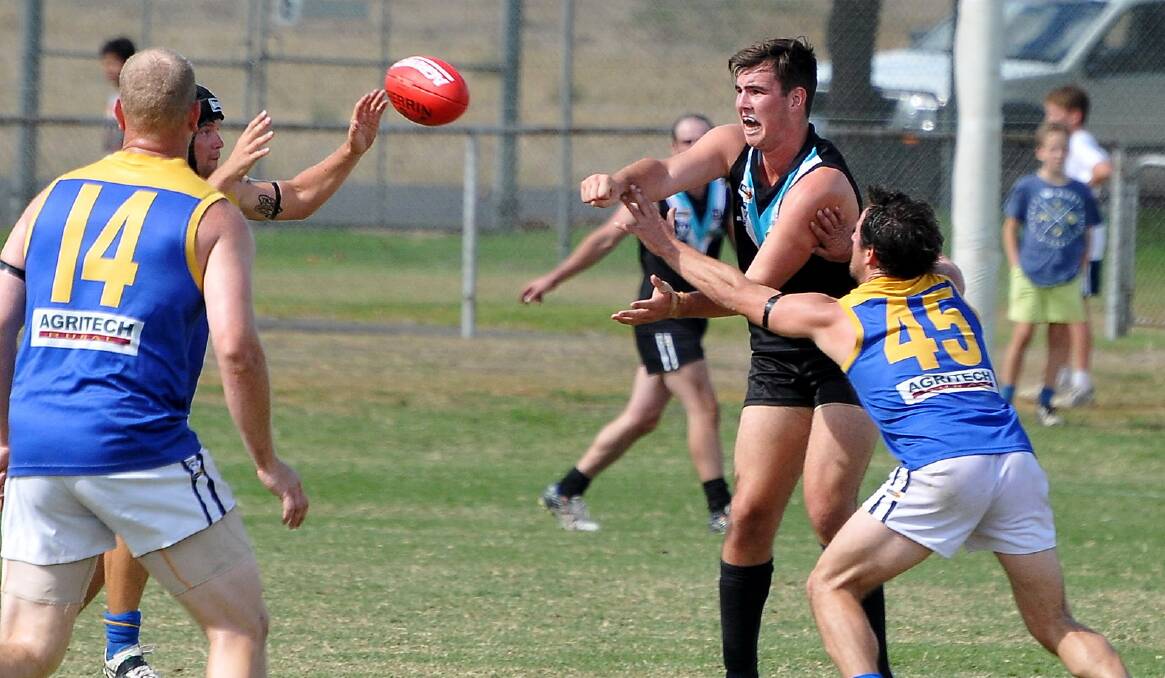 CKS Swifts ruckman Matt Healy manages to get this handball away despite being surrounded by Natimuk United players in Saturday's opening round clash of the Horsham District Football League. Picture: MARK McMILLAN.