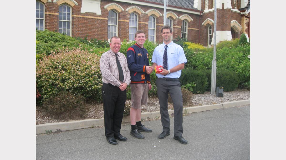Student Cameron Bowman who is bound for Gallipoli, receives his new camera from Harvey Norman representative Josh Bywater, while college principal Murray Hart looks on.