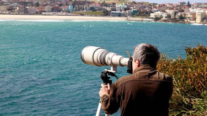 Photographer Ben Rushton takes a photo of Gabriella Duddy on North Bondi from St Peters park with a high-power lens.
