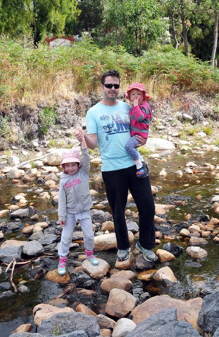 Matilda, Trevor and Lily Gillespie navigate the stones to cross Stony Creek in Halls Gap.