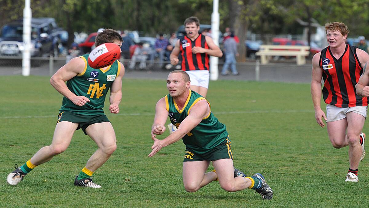 Navarre's Ben Scott was on his knees, but was desperate to get the handball out during Saturday's preliminary final clash against Maldon at Maryborough. Navarre, with a 23-point win, made their way into their second consecutive MCDFL grand final where they will meet Carisbrook this Sunday. Picture: MARK McMILLAN