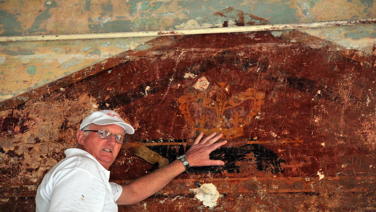Terry Dunn inspects the wall and painted detail of a crown and bible discovered during restoration works at the Stawell Church of Christ. Picture: KERRI KINGSTON